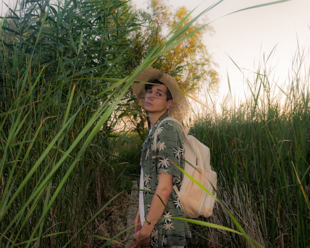 a man in a hat is standing in tall grass