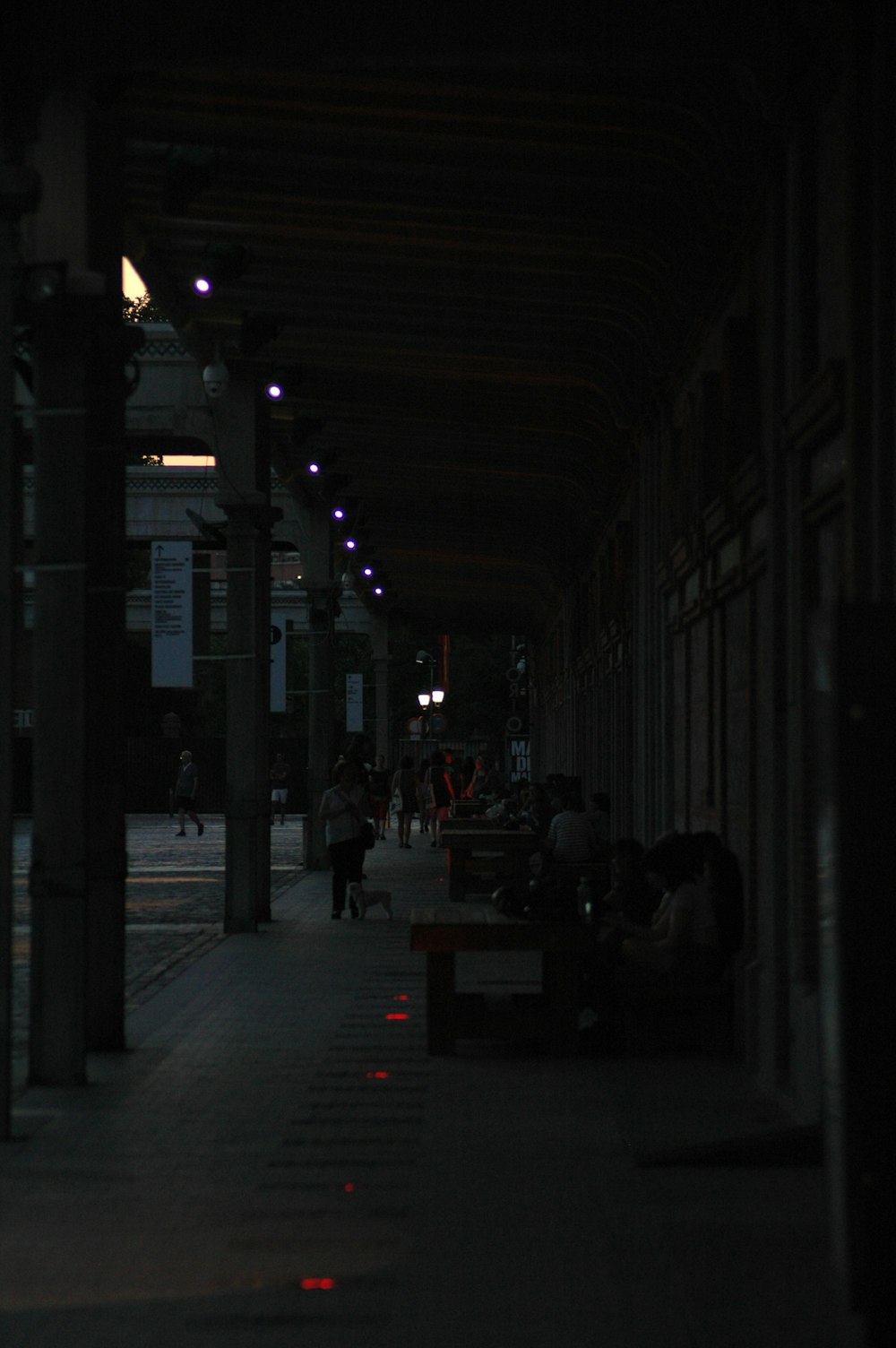 people are sitting on benches under a covered walkway