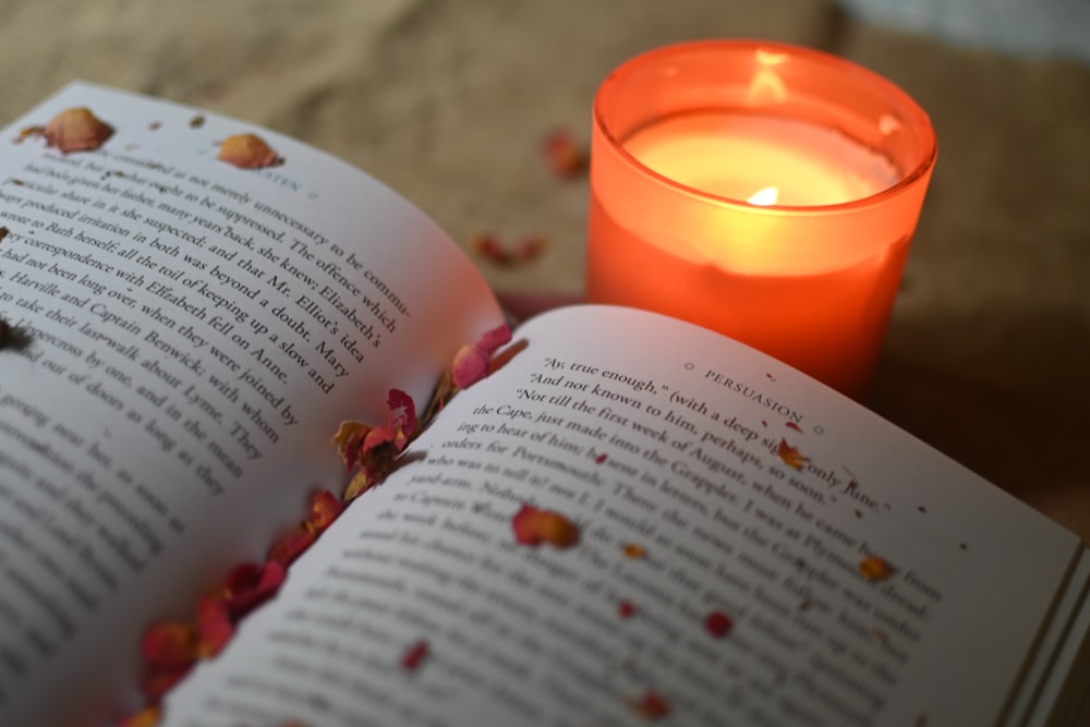 an open book next to a candle on a table