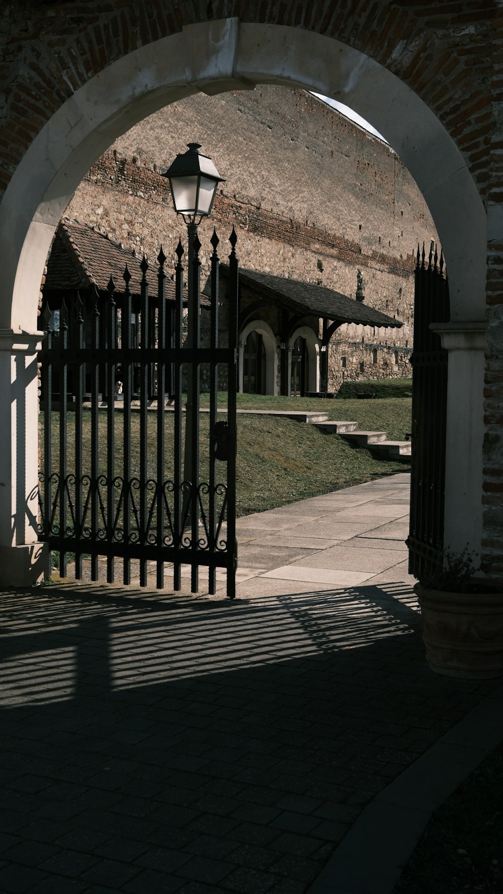 a gate with a light on it and a building in the background