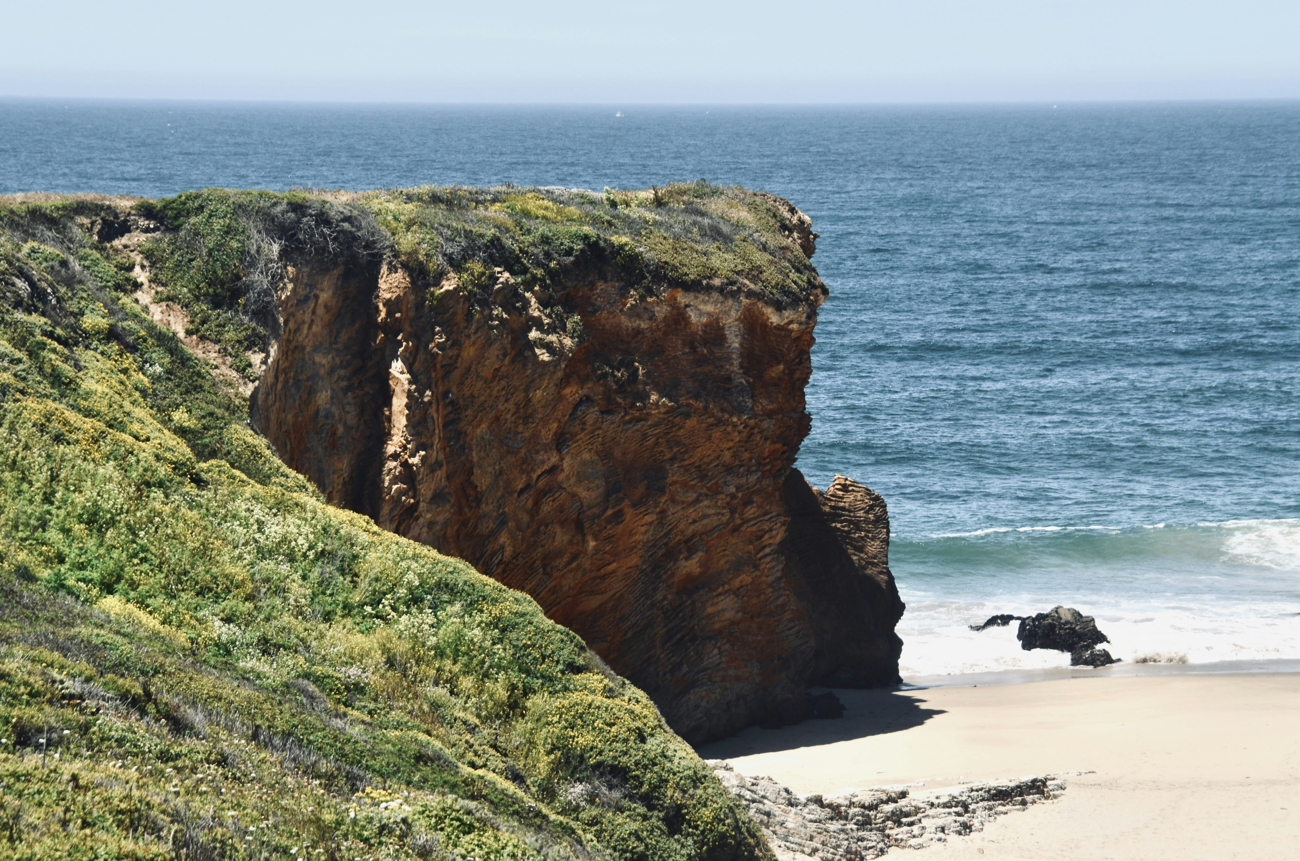 a large rock sticking out of the side of a beach