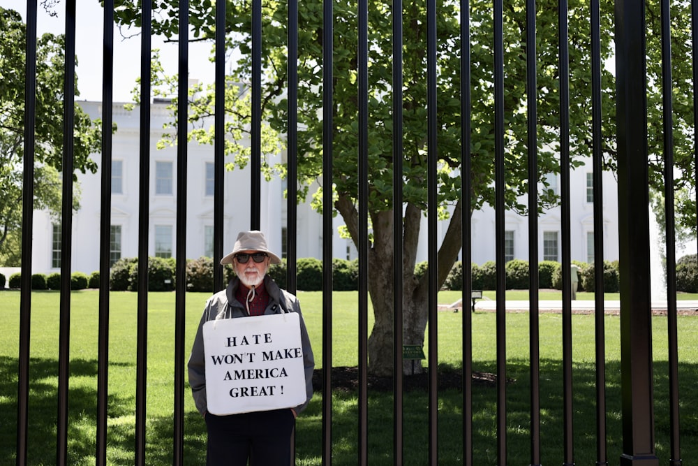 a man holding a sign that says hate won't make america great