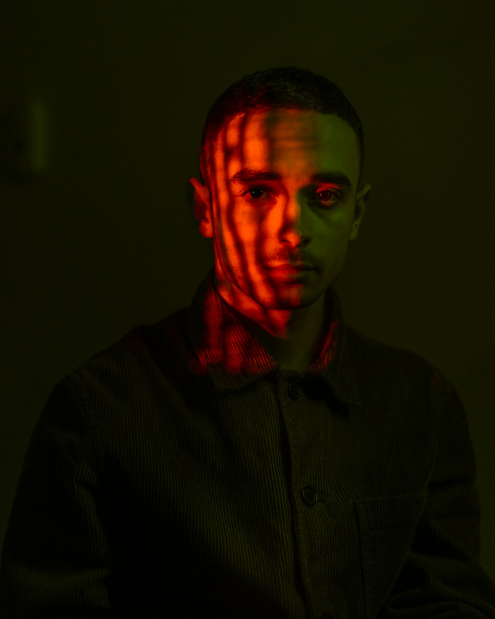 a man standing in a dark room with a red light on his face