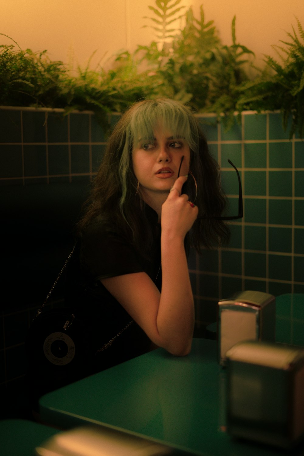 uma mulher com cabelo verde sentada em uma mesa