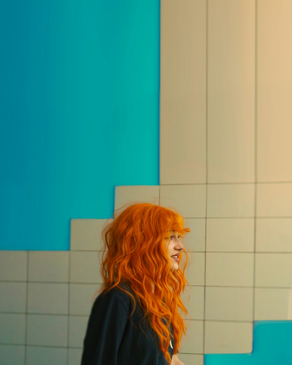 a woman with red hair standing in front of a blue and white wall