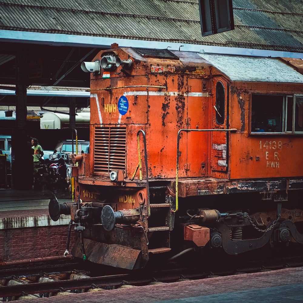 a rusted orange train sitting on the tracks