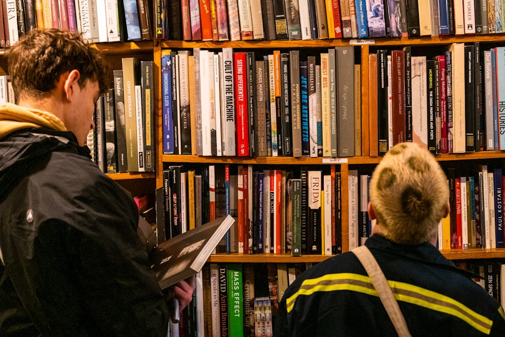 a man standing in front of a book shelf filled with books