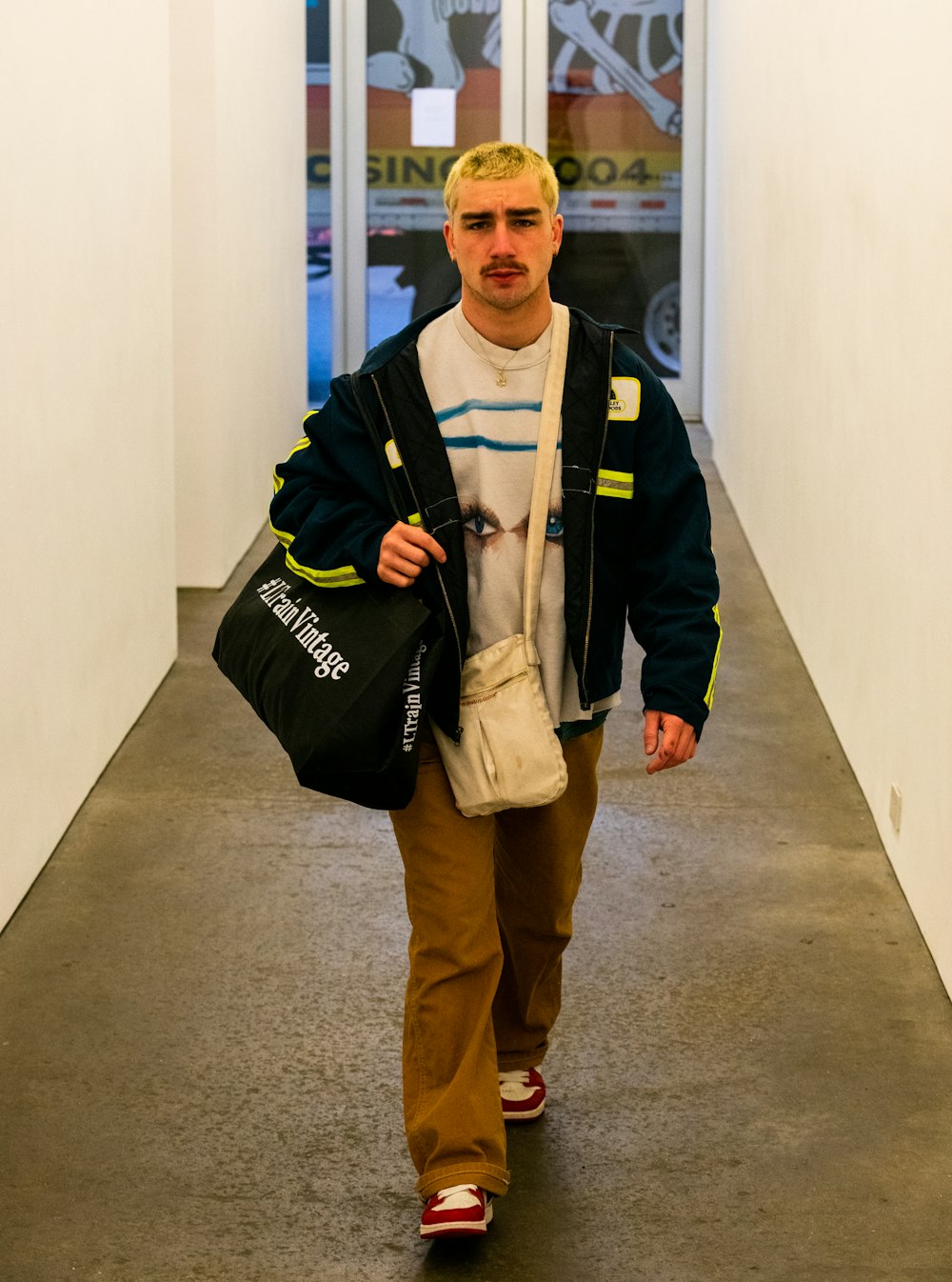 a man walking down a hallway carrying a bag