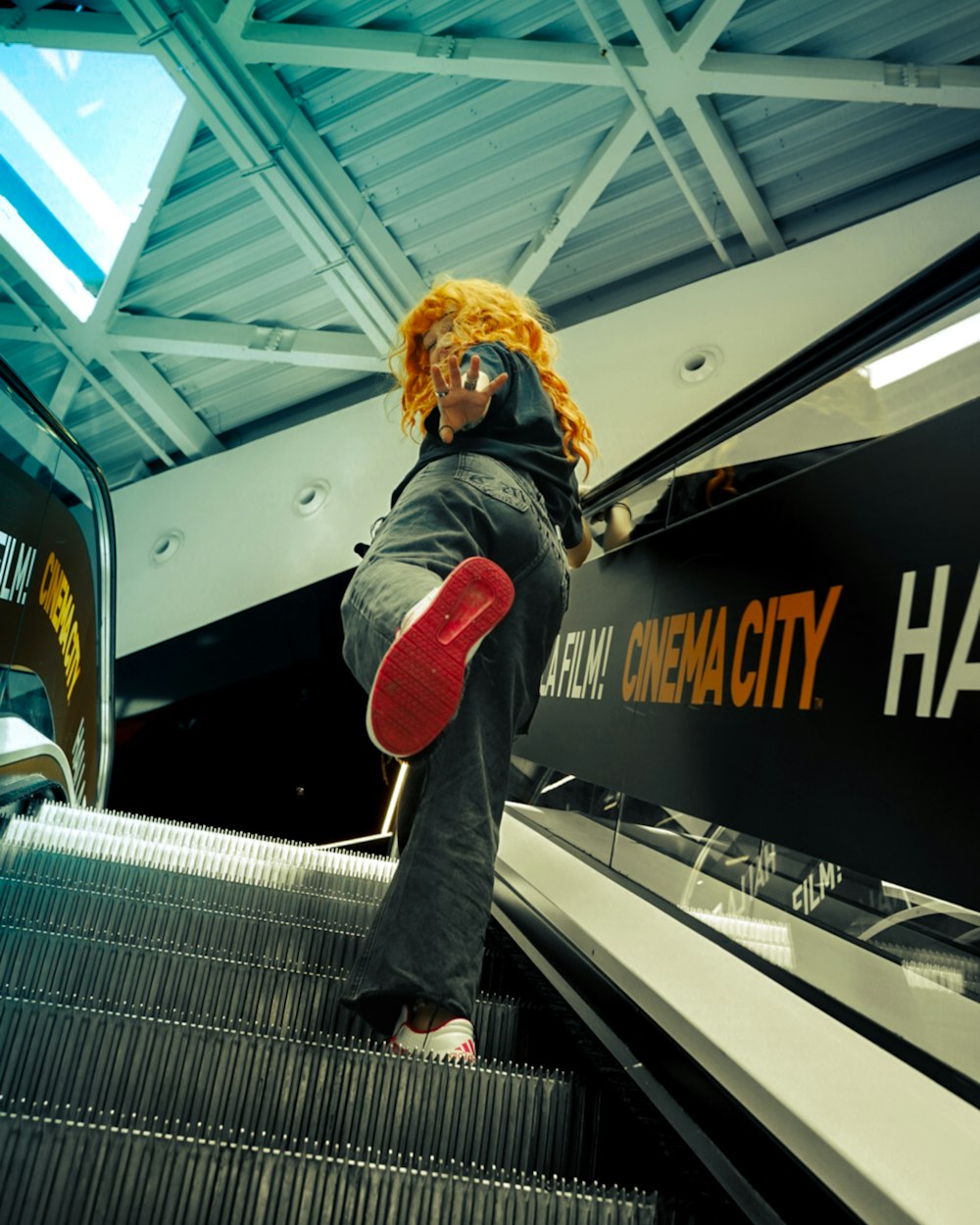 a person riding an escalator with a red skateboard