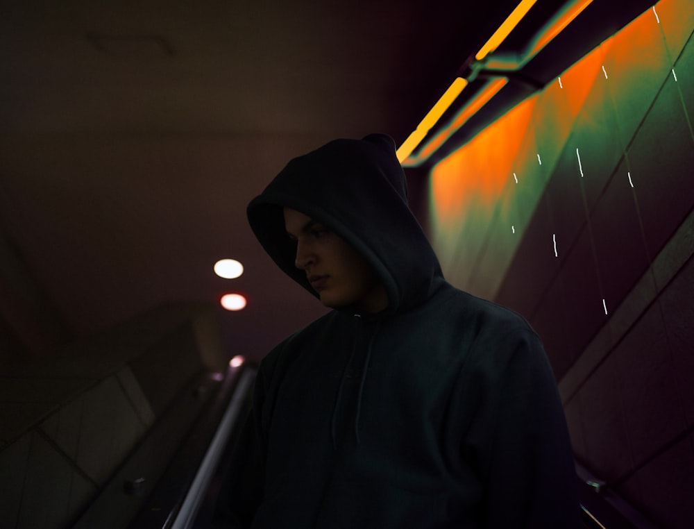 a man in a black hoodie standing in a hallway