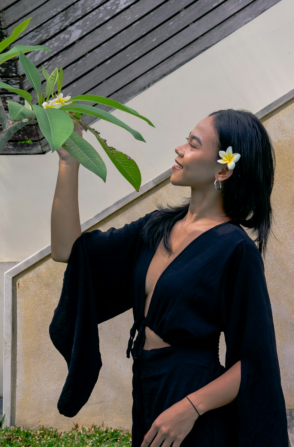 a woman in a black dress holding a plant