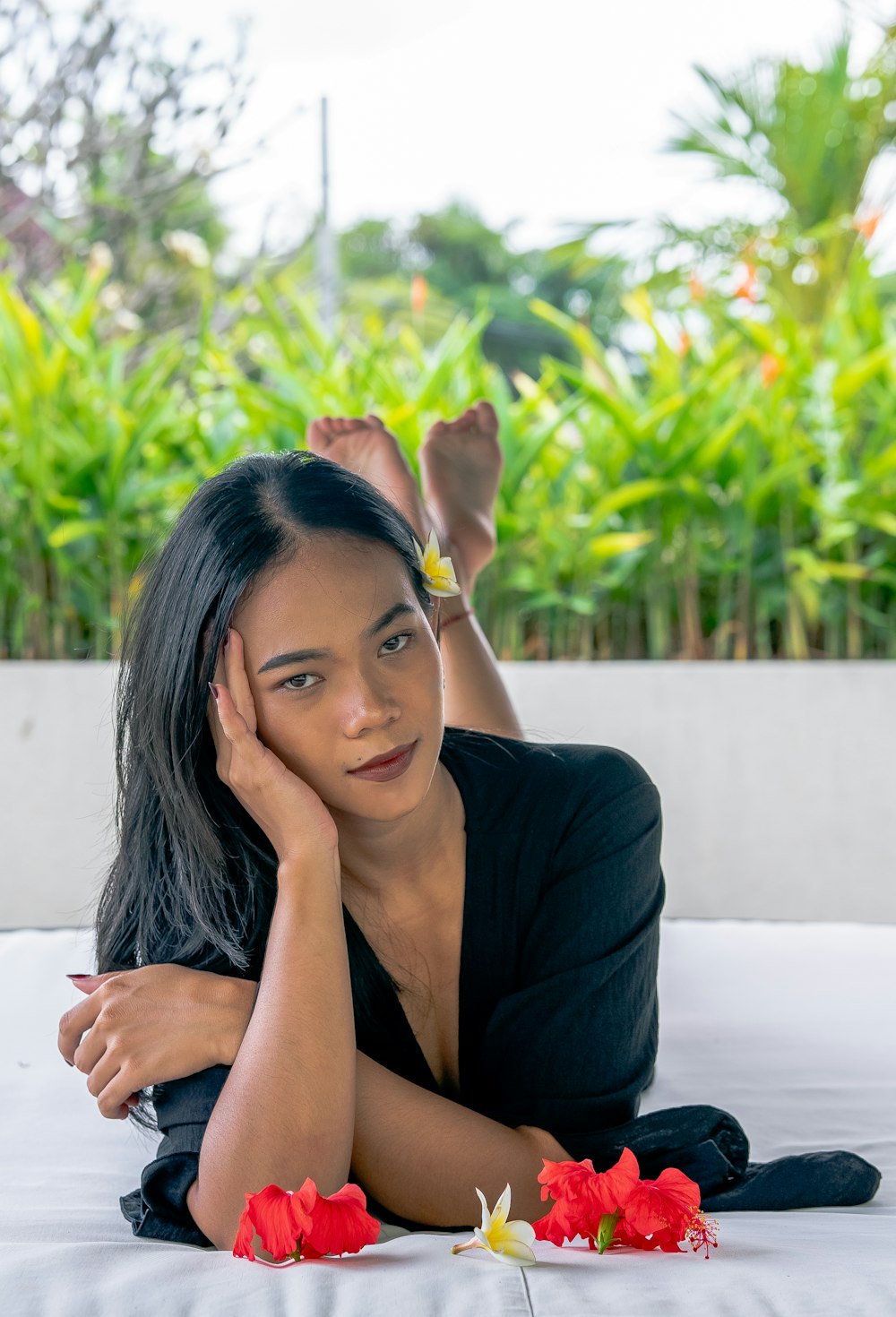 a woman laying on top of a bed next to flowers