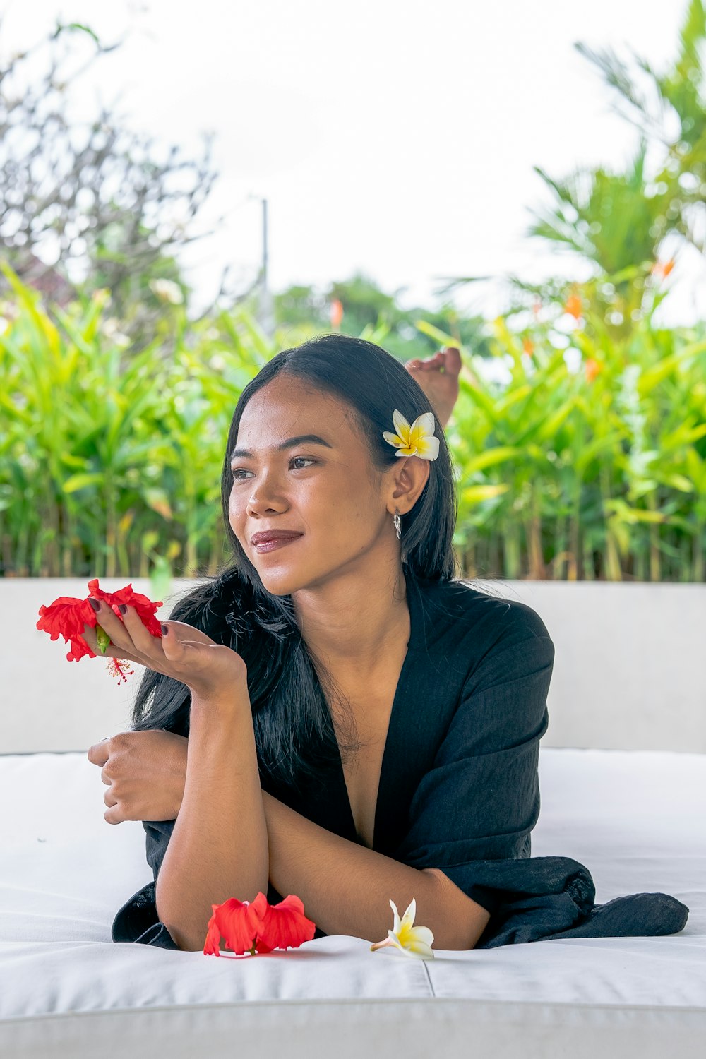 a woman sitting on a bed with flowers in her hair