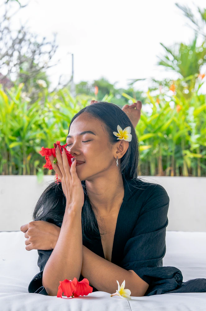 Woman receiving a Balinese spa treatment surrounded by tropical flowers