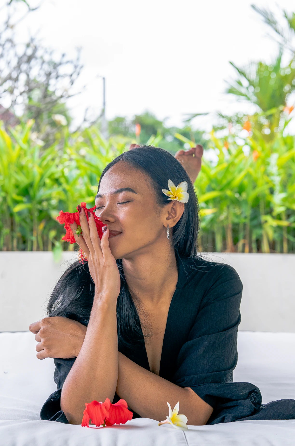 a woman laying on a bed with flowers in her hair