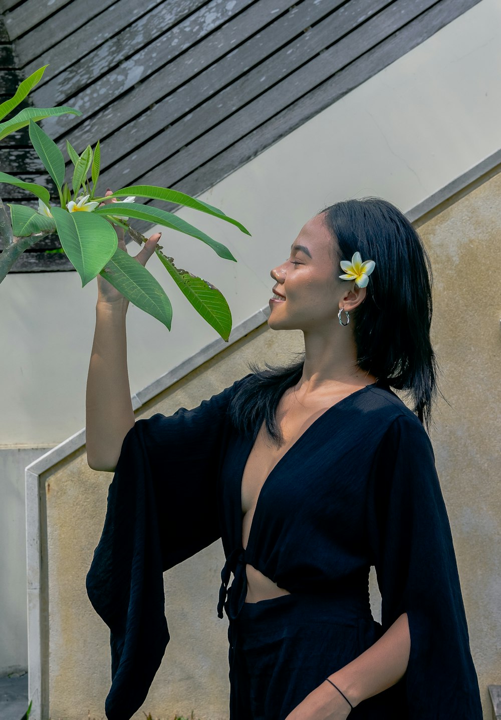 a woman in a black dress holding a plant