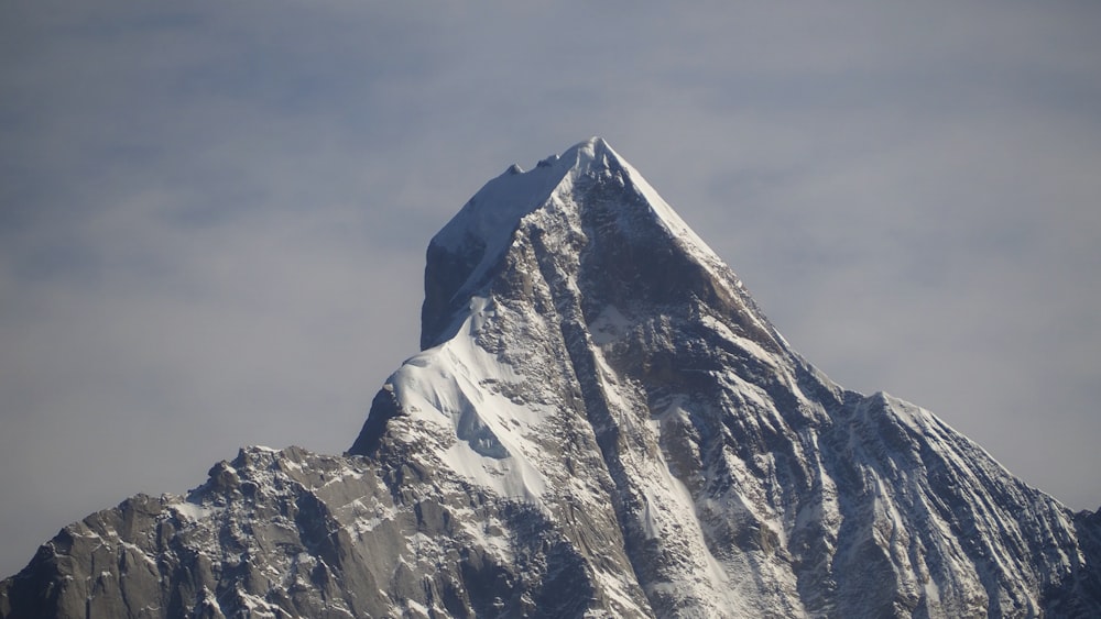 a very tall snow covered mountain with a sky background