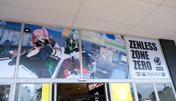 An animated promotional banner for Zenless Zone Zero features colorful characters and dynamic artwork displayed above glass doors. A pink-haired character with futuristic attire sits on a vehicle, while other animated figures appear around it. The banner includes bold text with the game’s title.