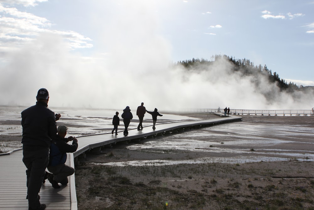 a group of people walking across a boardwalk