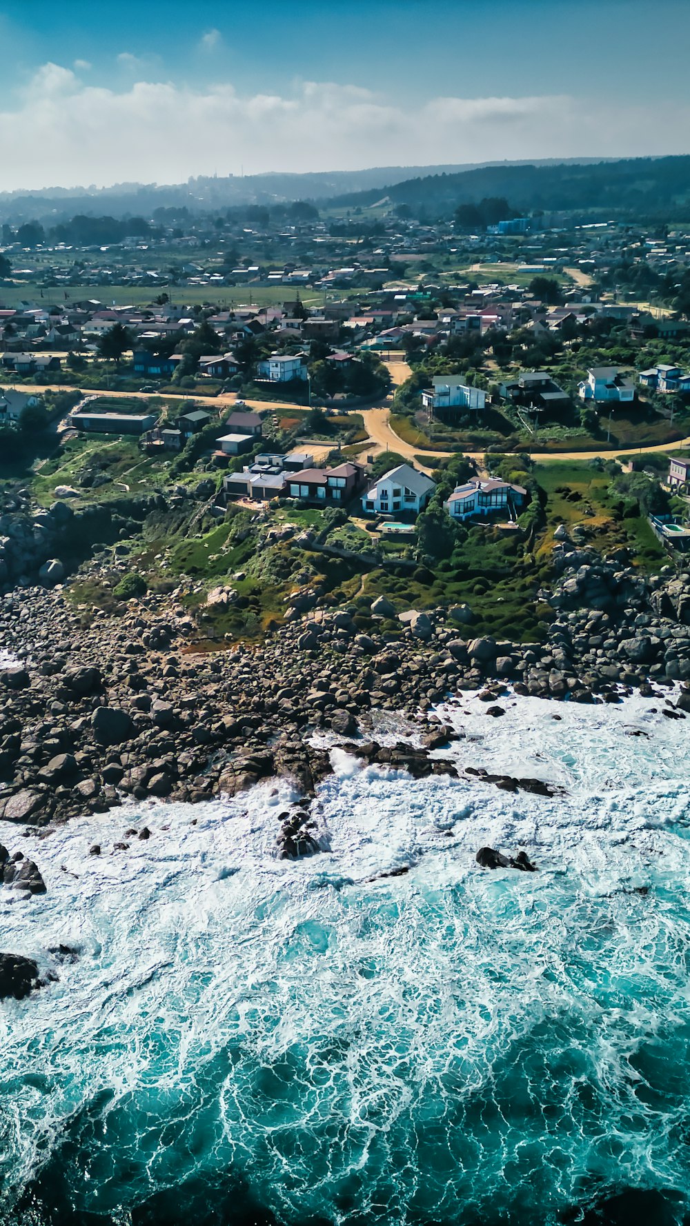 an aerial view of the ocean with houses in the background