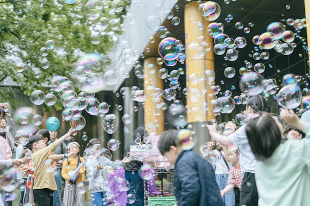 Energetic participants enjoying a colorful Bubble Bash event outdoors with bubbles floating in the air.