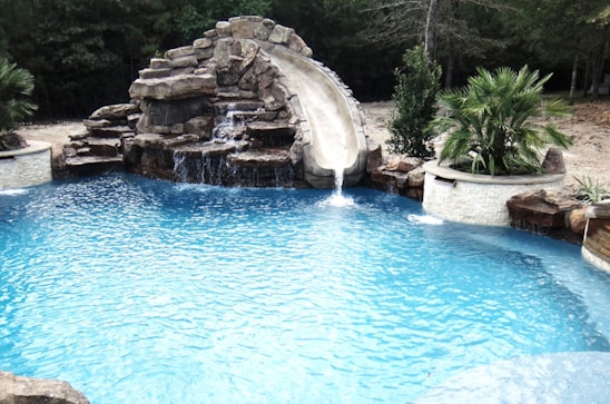 a Central Texas swimming pool with a waterfall and a slide