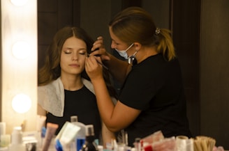 a woman getting her make up done in front of a mirror