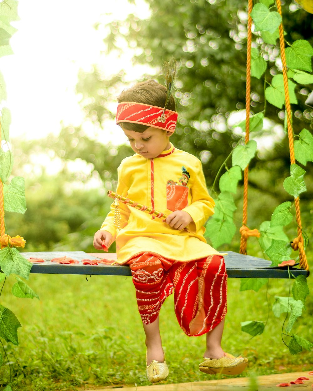 a little girl sitting on a swing in the grass