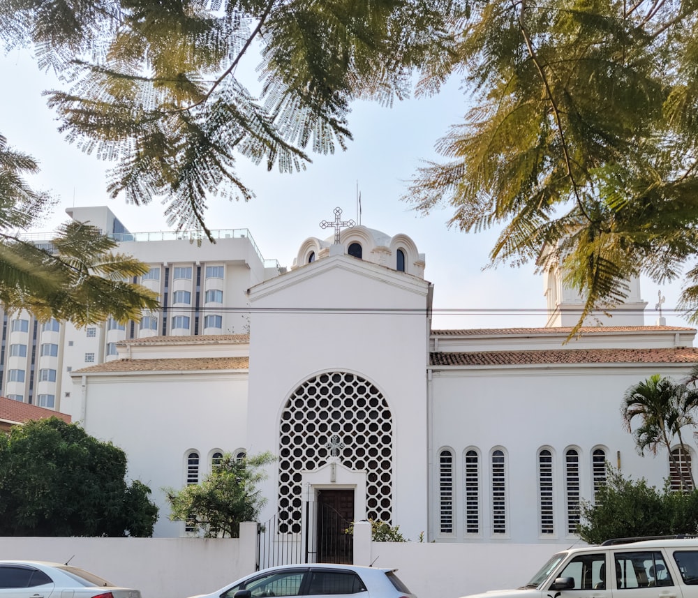 un grande edificio bianco con auto parcheggiate di fronte ad esso