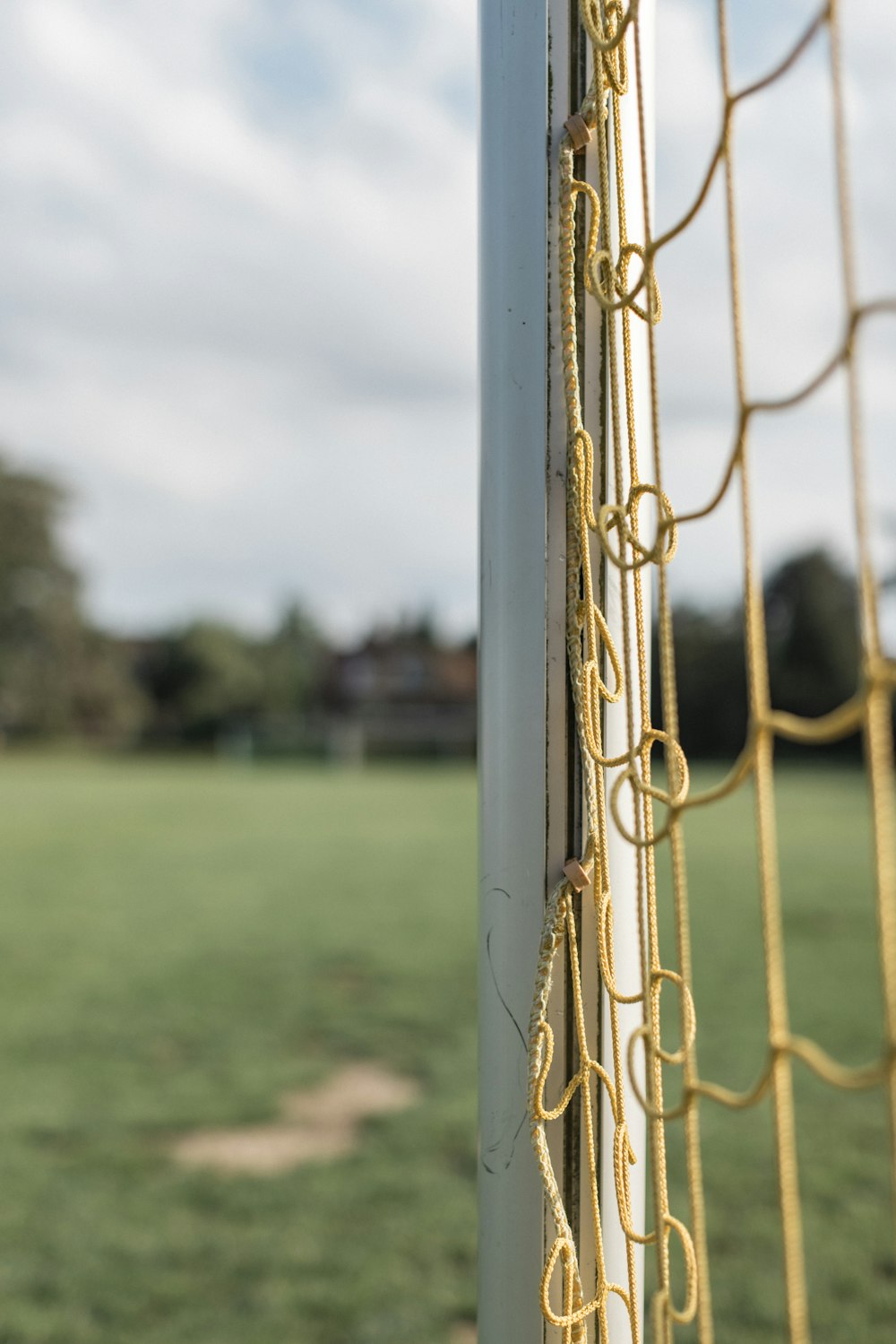 a close up of a soccer goal net with a field in the background