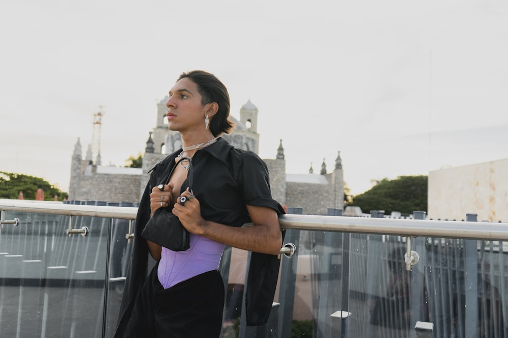 a woman standing on a balcony holding a purple bag