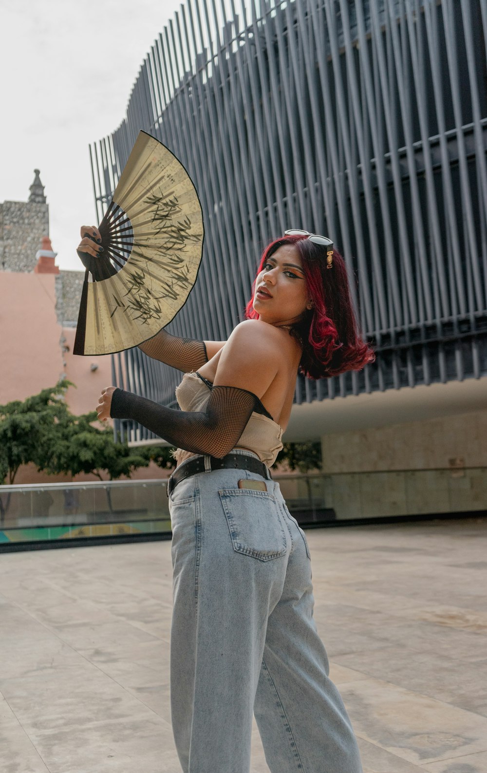 a woman with red hair is holding a fan