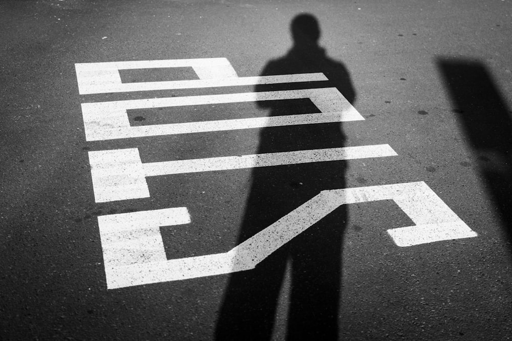 a shadow of a person standing in the middle of a street