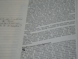 A close-up of a page from a book with printed text and handwritten notes in the margins. The text appears to be in English and consists of paragraphs, while the handwritten notes include a question.