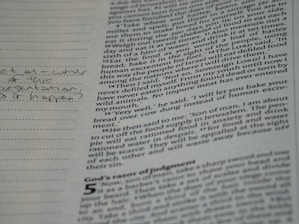 A close-up of a page from a book with printed text and handwritten notes in the margins. The text appears to be in English and consists of paragraphs, while the handwritten notes include a question.