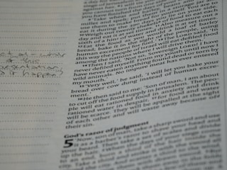 A close-up of a page from a book with printed text and handwritten notes in the margins. The text appears to be in English and consists of paragraphs, while the handwritten notes include a question.