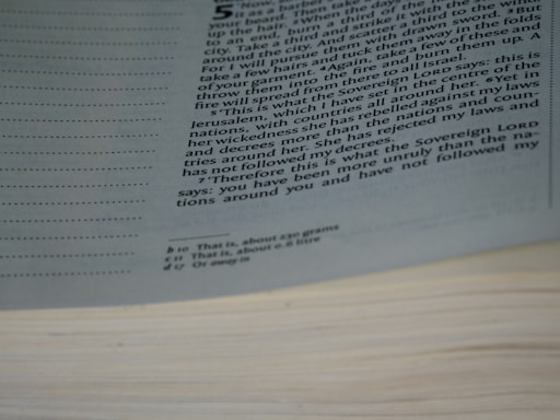 A close-up view of a page from an open book, displaying printed text in multiple paragraphs. The text is partially obscured by the page curvature. Margins contain dotted lines, and there are footnotes or annotations at the bottom of the page.