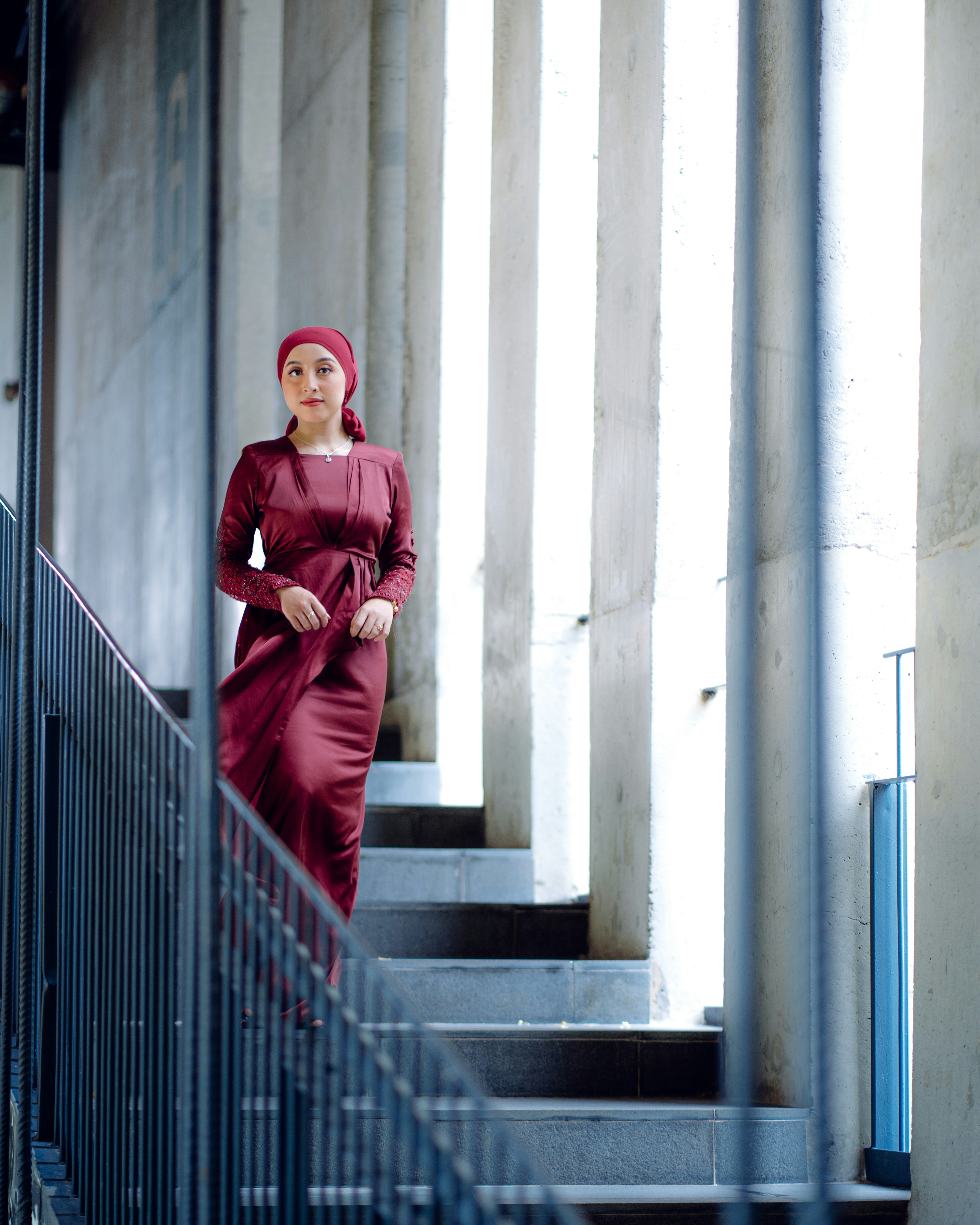 a woman in a red dress is standing on a set of stairs