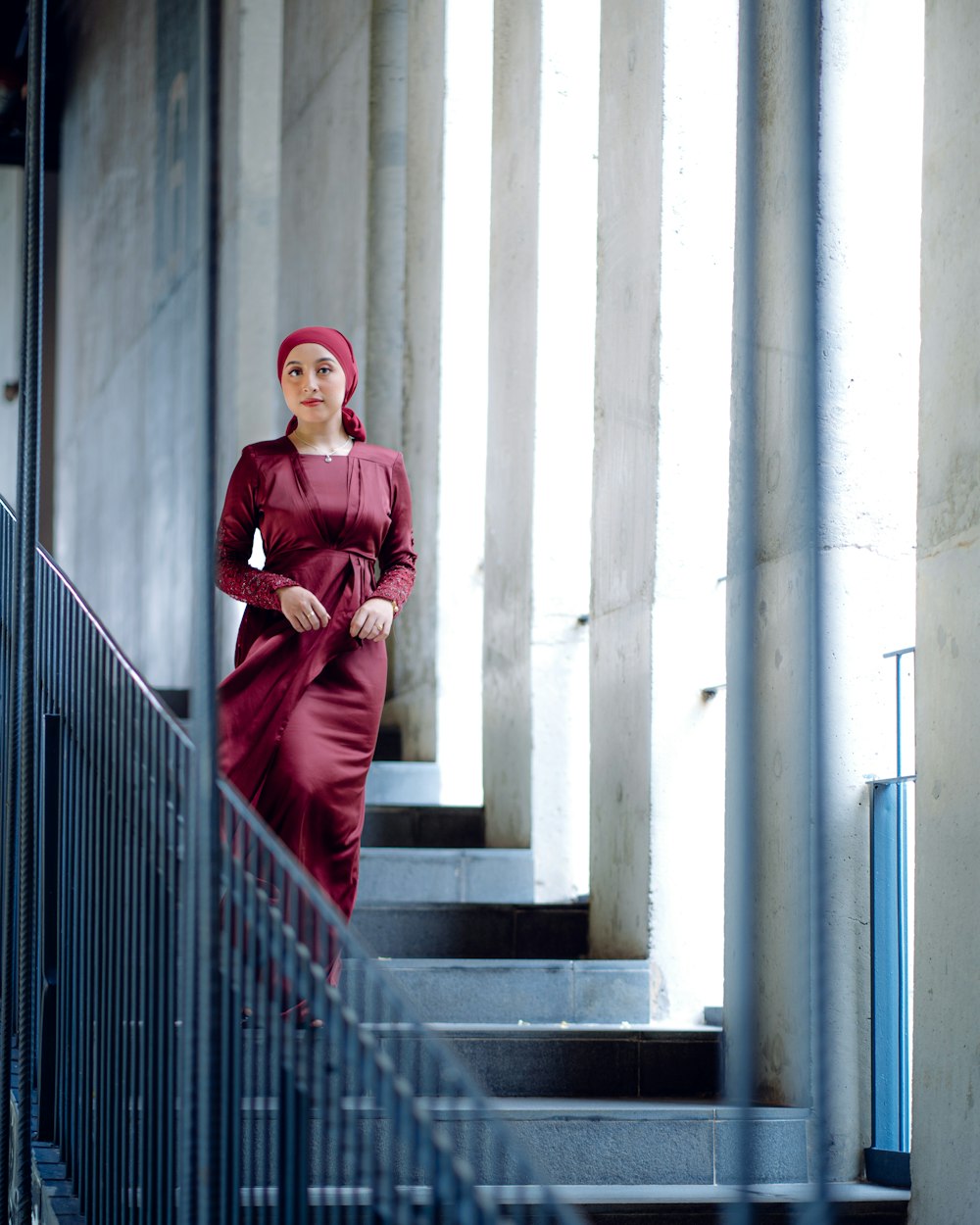 a woman in a red dress is standing on a set of stairs