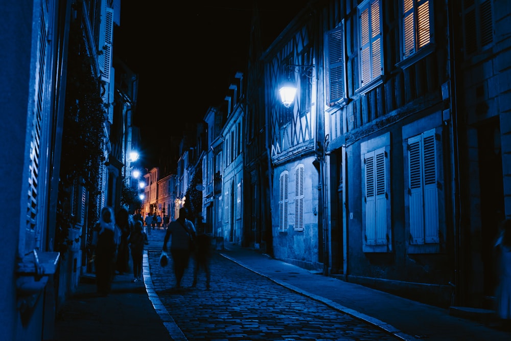 a group of people walking down a street at night