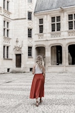a woman in a red skirt is standing in front of a large building