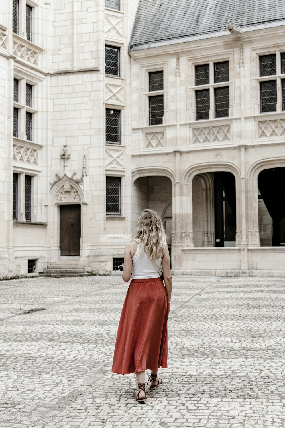 Uma mulher de saia vermelha está em frente a um grande prédio