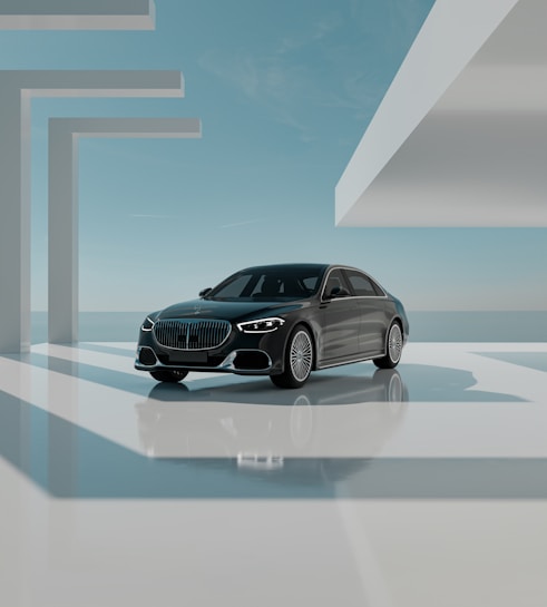 A sleek black luxury car is positioned in a modern, minimalistic architectural environment. The setting features geometric shapes and large, open spaces bathed in natural light. The sky is clear with subtle clouds, creating a serene backdrop. The car is prominently displayed, reflecting light off its polished surface.