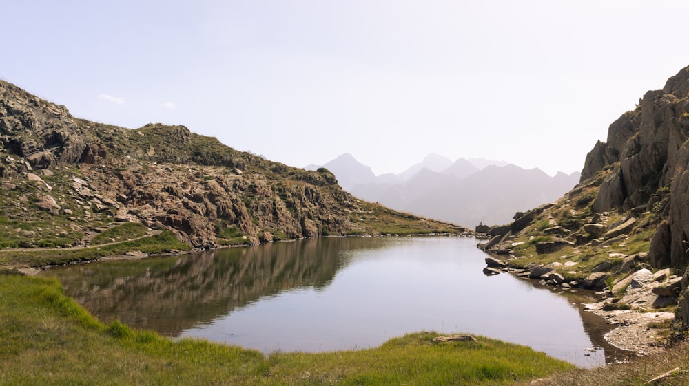 un petit lac entouré de montagnes et d’herbe