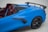 A sleek, blue sports car showcasing its aerodynamic design with a prominent rear spoiler, black rims, and a vibrant red interior. The image emphasizes the car’s modern and sporty aesthetic.