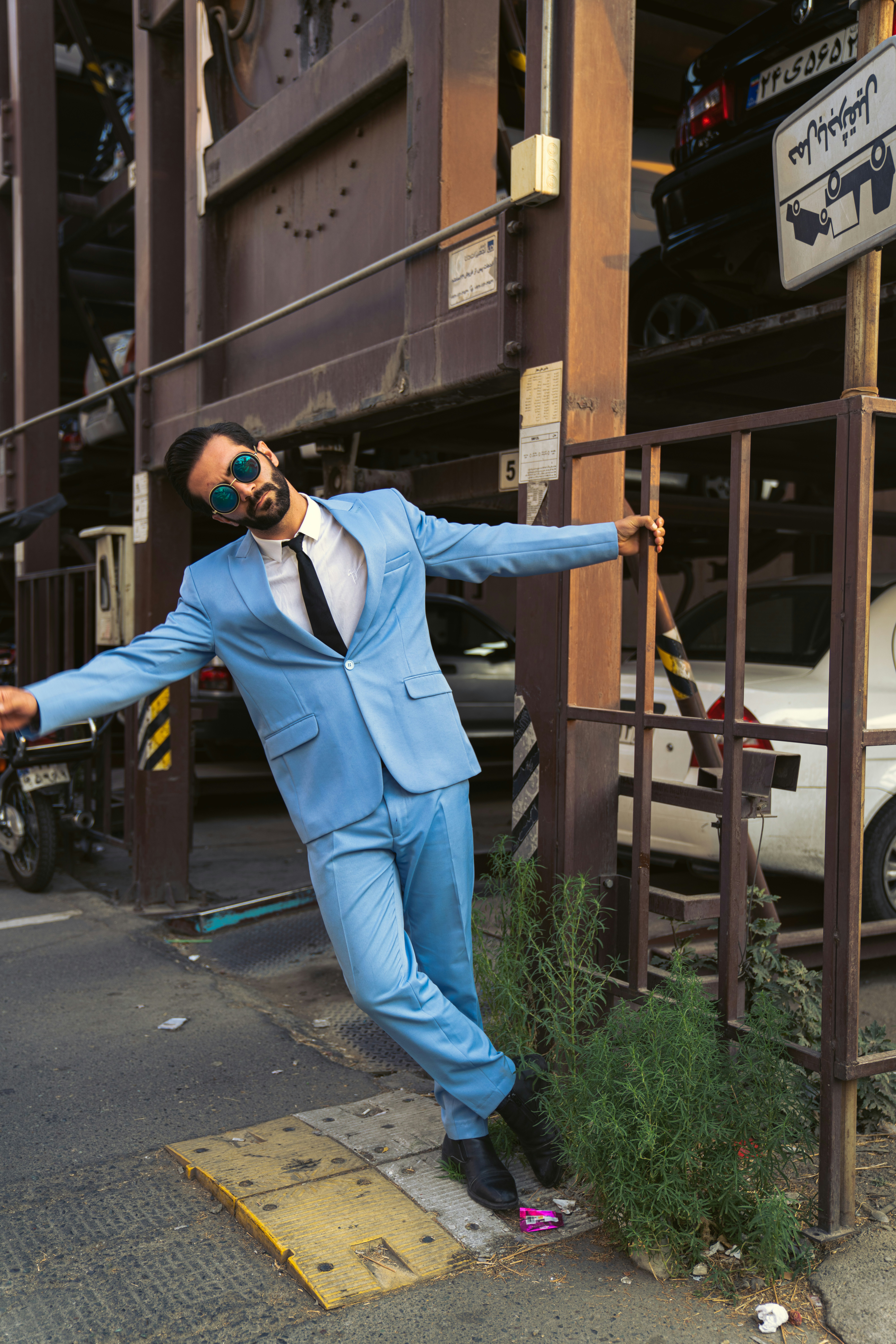A man in a blue suit leaning against a fence photo – Free Man Image on ...