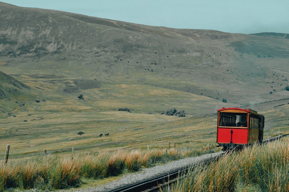 Un tren rojo que viaja a través de un exuberante campo verde