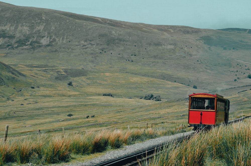 a red train traveling through a lush green countryside