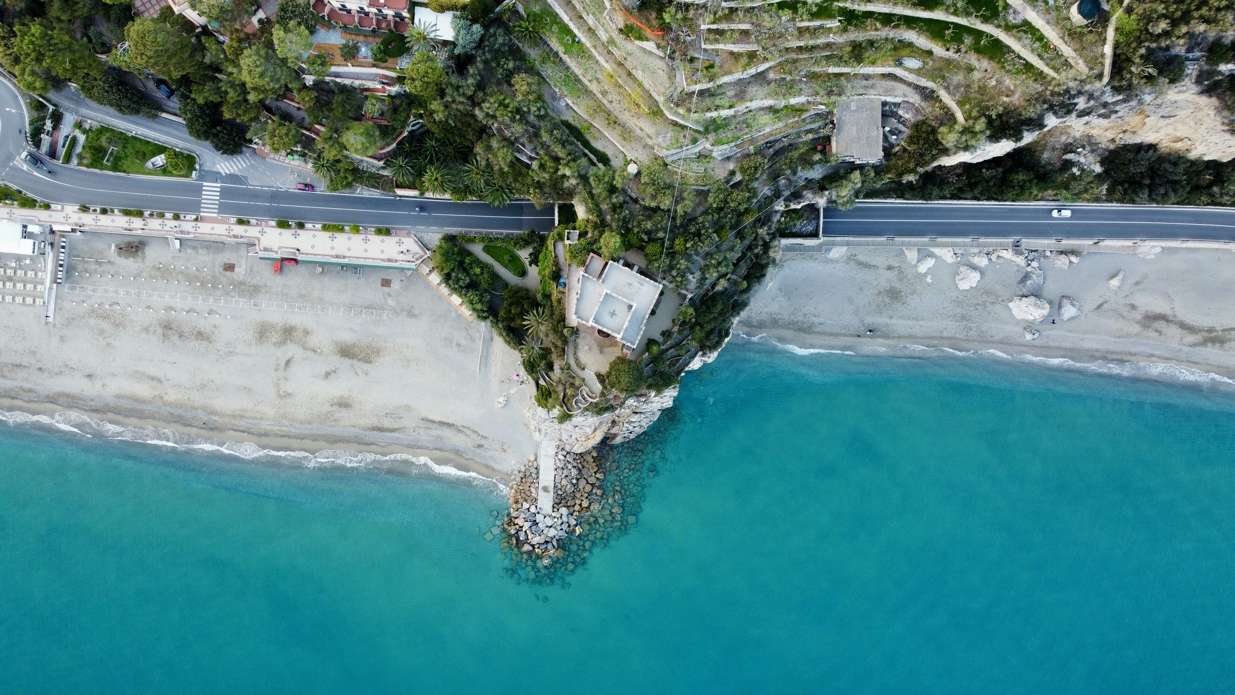 an aerial view of a road next to a body of water