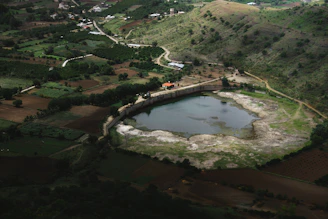 A freshly dug pond nestled in a rural landscape with earthmoving equipment nearby.